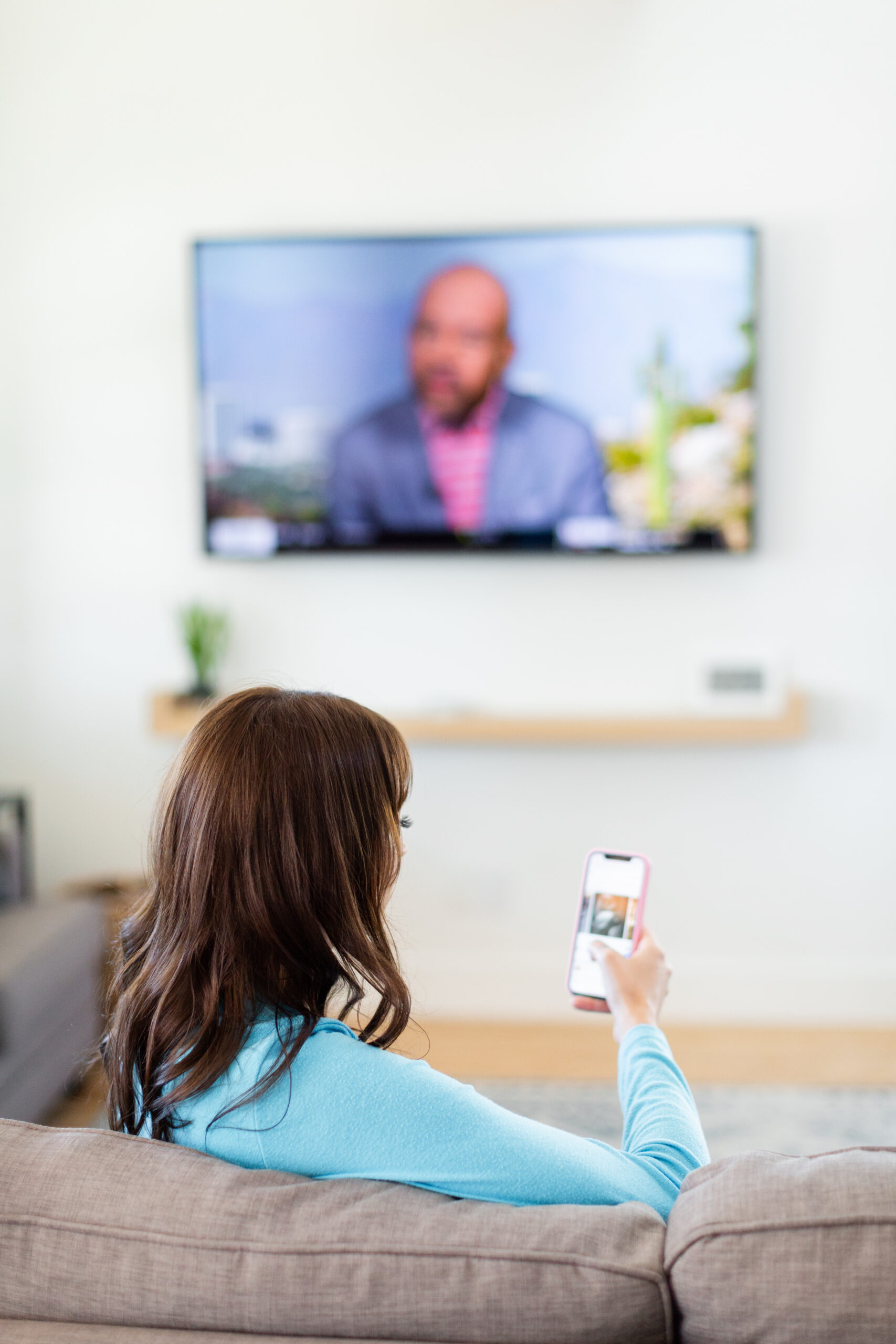 Woman looking at phone while watching TV